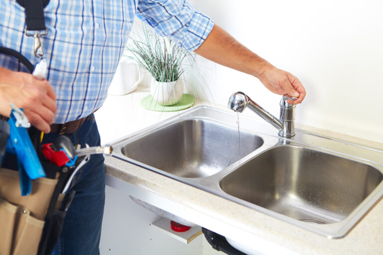 plumber-with-blue-plaid-shirt-and-tool-belt-using-sink-after-repair