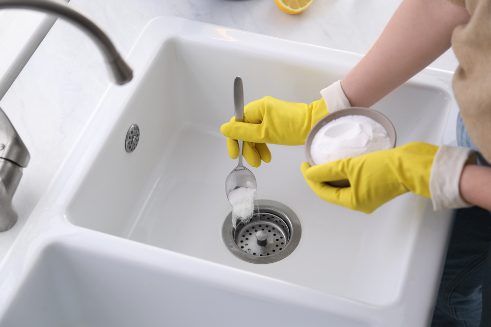 Woman using baking soda to unclog sink drain