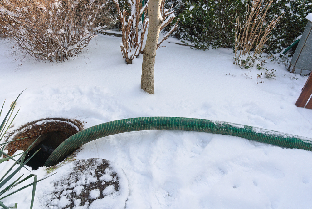 Green hose running into septic tank in the winter
