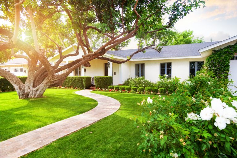 White house with beautifully manicured front lawn and garden