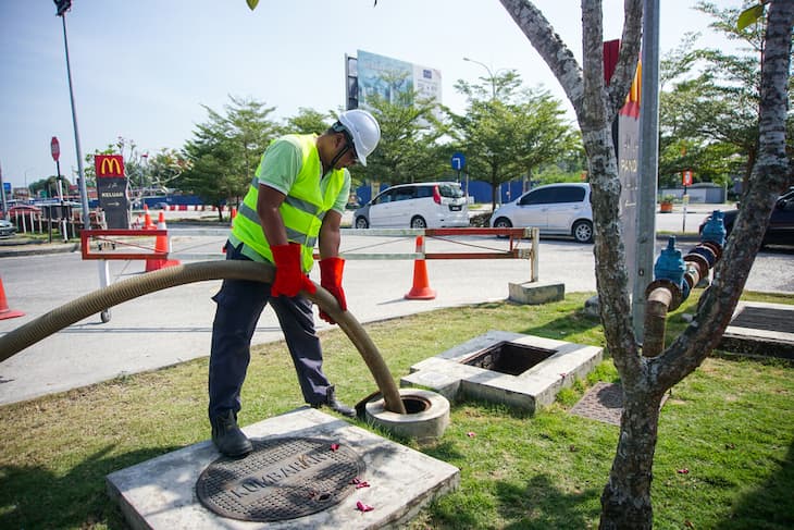 Staff wearing reflective vest and helmet repairing trenchless sewer