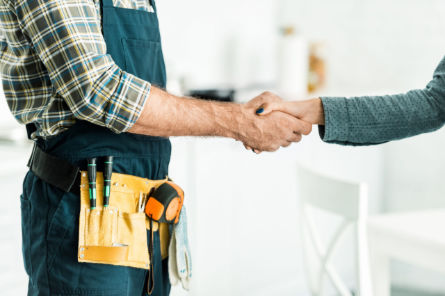 Professional plumber shaking hands with a homeowner after completing a water line repair service.
