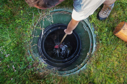 Worker inspecting the inside of a septic tank to check for blockages or required maintenance.