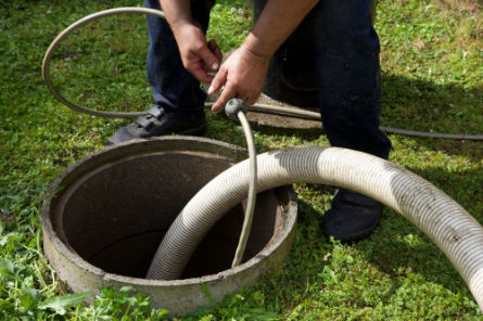 Professional performing septic tank pumping using a vacuum hose – Peak Sewer septic maintenance and repair.