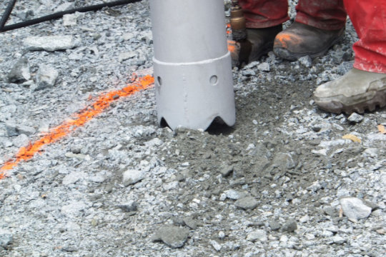 Hydrovac excavation nozzle removing gravel during non-destructive digging for underground utilities.