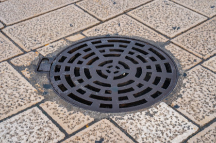 Manhole cover providing access to underground utilities commonly serviced with hydrovac excavation.