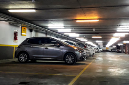 Underground parking garage with lined parking spaces, showing areas prone to drainage and grease buildup.