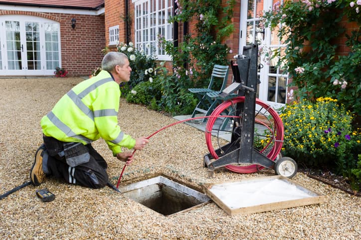 Drainage technician performing a residential sewer line inspection outdoors